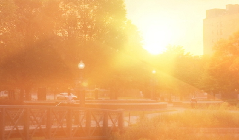 Sunlight reflects over a river and pedestrian bridge in downtown Kalamazoo, capturing a warm, peaceful moment in southwest Michigan.