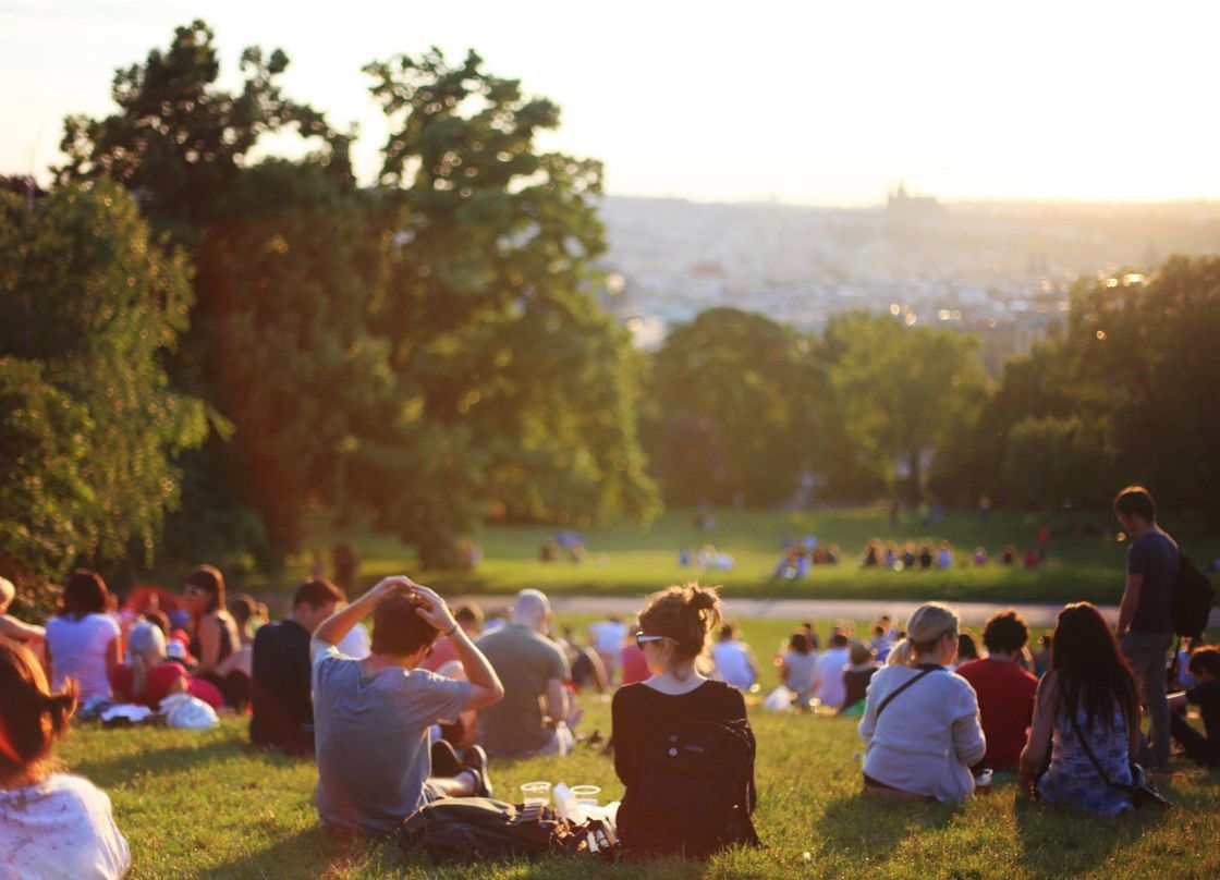people sitting on a lawn in a park during golden hour