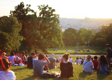 people sitting on a lawn in a park during golden hour