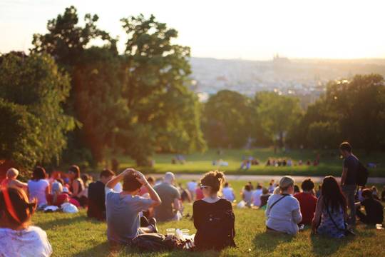 people sitting on a lawn in a park during golden hour